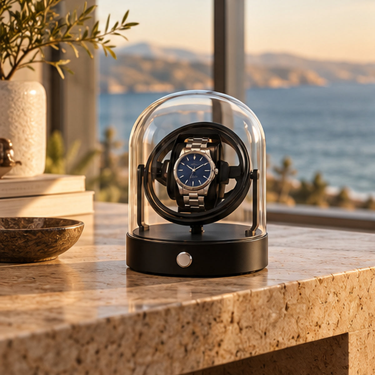 Remontoir Montre Gyroscopique 1 Place – Cloche en Verre – posé sur un plan en granit devant une baie vitrée avec vue mer