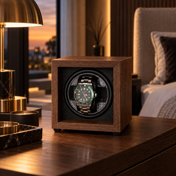Remontoir montre automatique 1 place en placage bois sur une table de chevet, lampe en laiton et vue sur la ville au crépuscule – Complications Paris